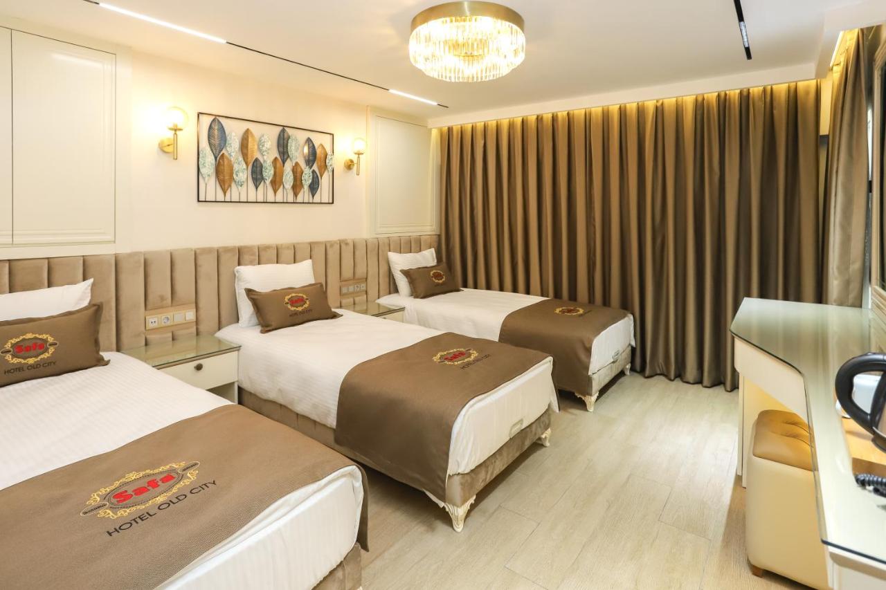 een hotelkamer met drie bedden en een kroonluchter bij Safa Hotel Old City in Istanbul
