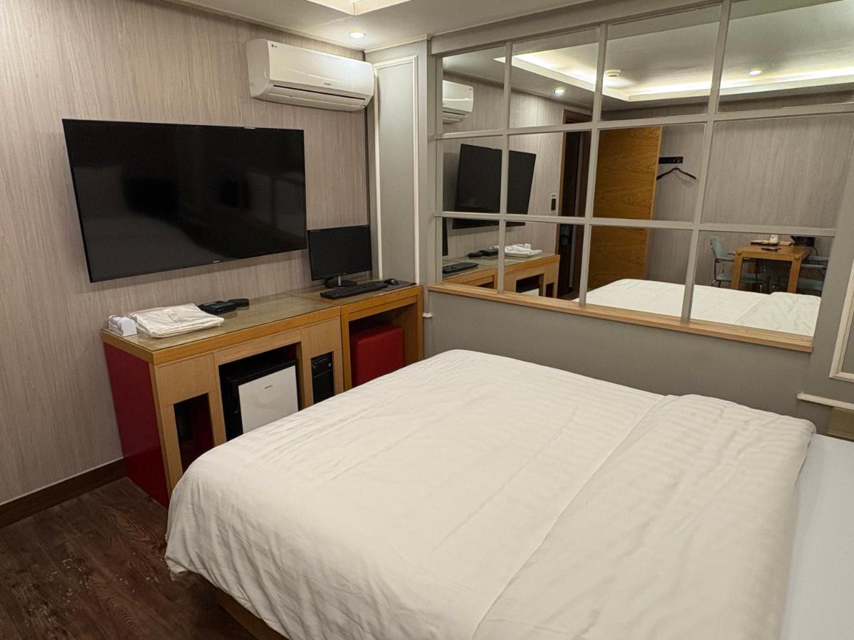 een slaapkamer met een bed en een grote spiegel bij Rosemari Hotel in Seoul