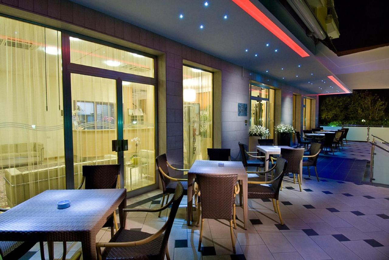 een restaurant met tafels, stoelen en ramen bij Hotel St. Moritz in Bellaria-Igea Marina