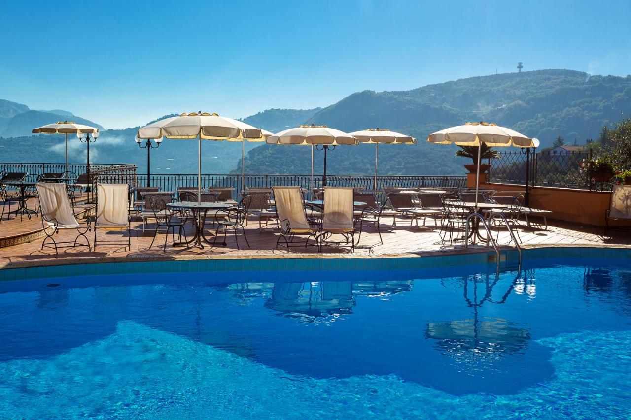 een zwembad met tafels, stoelen en parasols bij Hotel La Vue d'Or in Sorrento