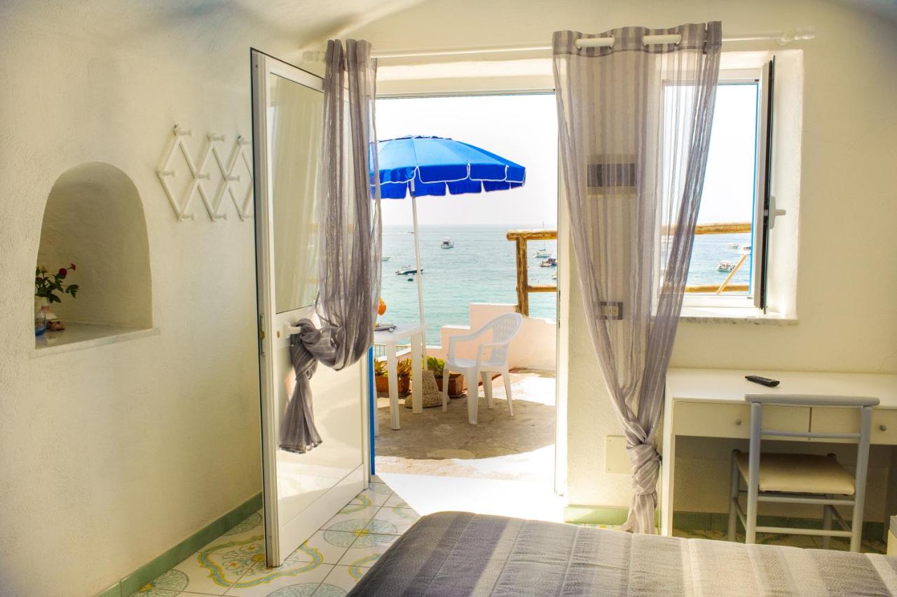 een slaapkamer met een deur die uitkijkt op de oceaan, met een parasol bij Hotel Regina del Mare in Barano dʼIschia