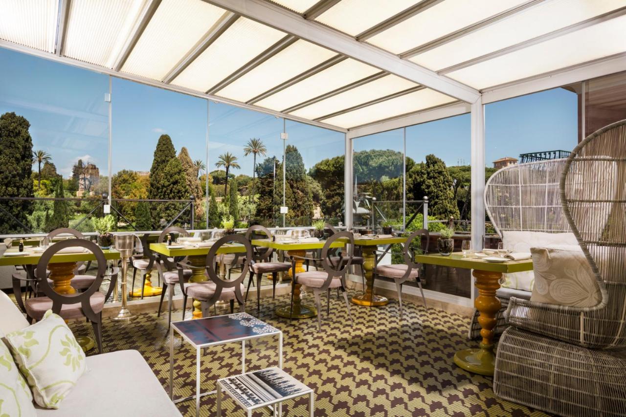 een restaurant met tafels en stoelen en grote ramen bij Hotel Palazzo Manfredi – Small Luxury Hotels of the World in Rom