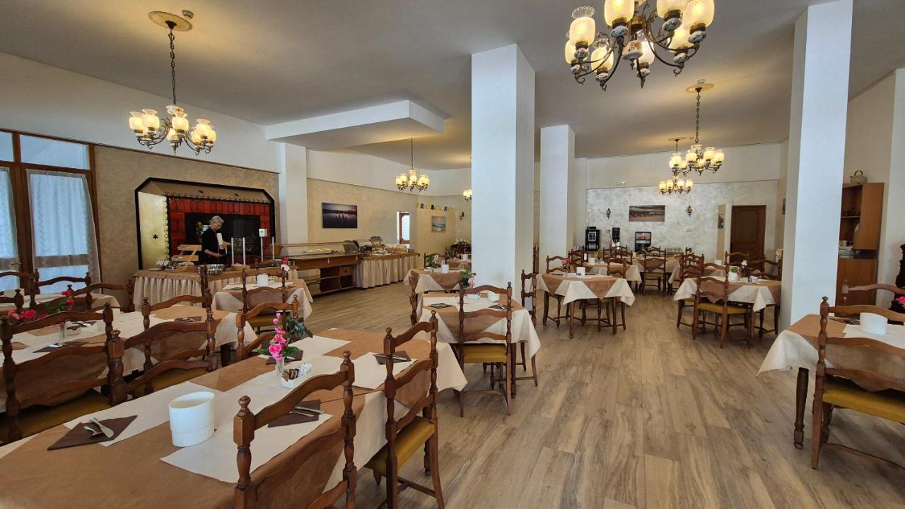 een restaurant met tafels en stoelen en een vrouw op de achtergrond bij Al Cavallino Bianco in Lignano Sabbiadoro