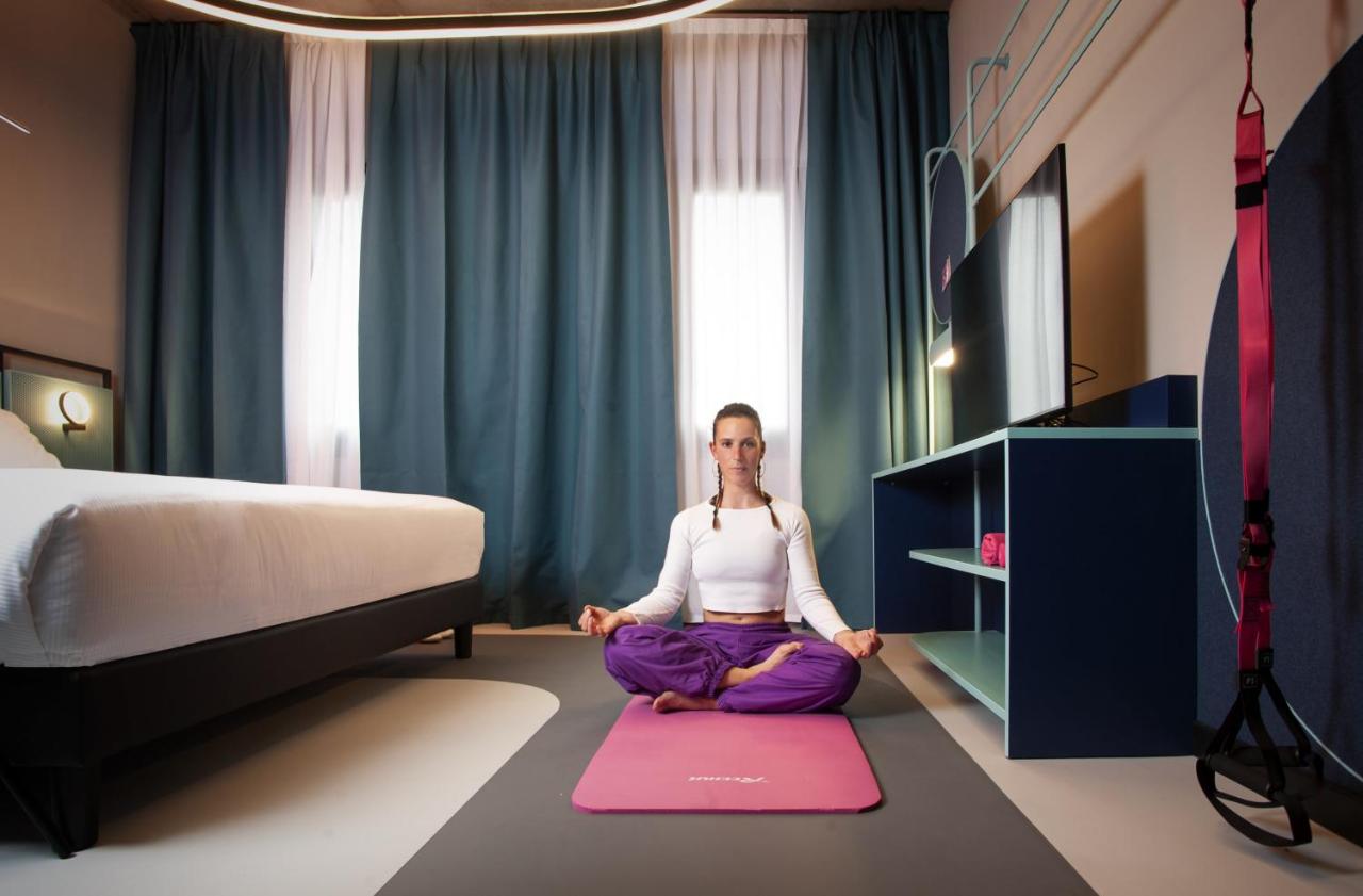 een vrouw zit op een kleed in een kamer met een bed bij Stay Hotel in Brunello