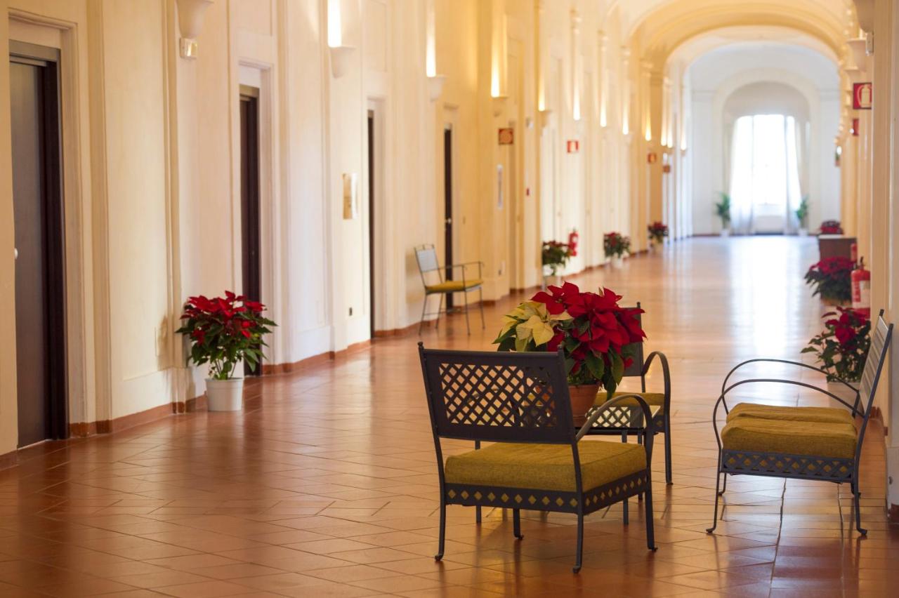 een gang met stoelen en bloemen in een gebouw bij Domus Sessoriana in Rome