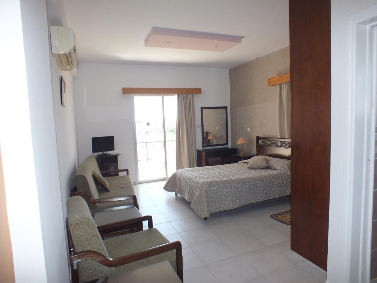 een slaapkamer met een bed en twee stoelen erin bij Petsas Apartments in Coral Bay