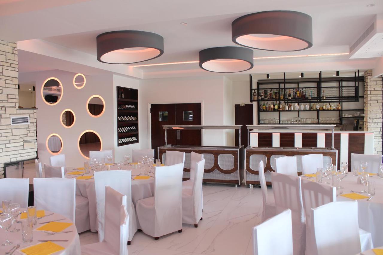 een eetkamer met witte tafels en witte stoelen bij Petsas Apartments in Coral Bay