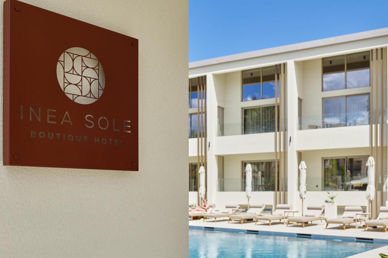 een bord aan de zijkant van een gebouw met een zwembad bij Inea Sole Boutique Hotel in Kato Daratso