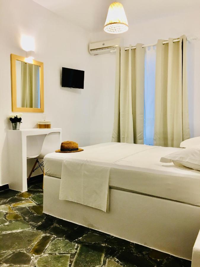 een slaapkamer met een bed, een bureau en een televisie bij Nostos Studios in Parikia