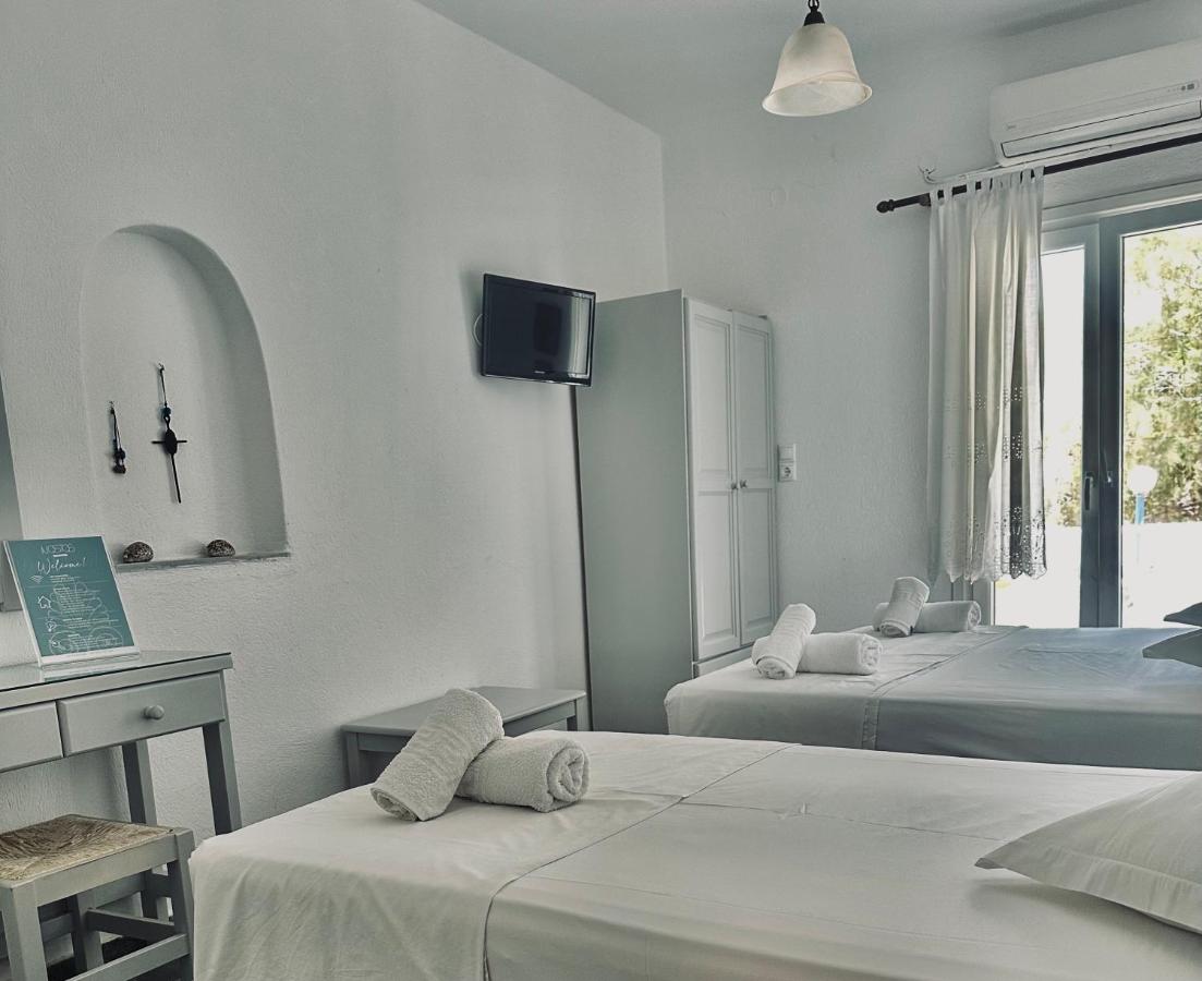 een slaapkamer met twee bedden, een bureau en een tv. bij Nostos Studios in Parikia