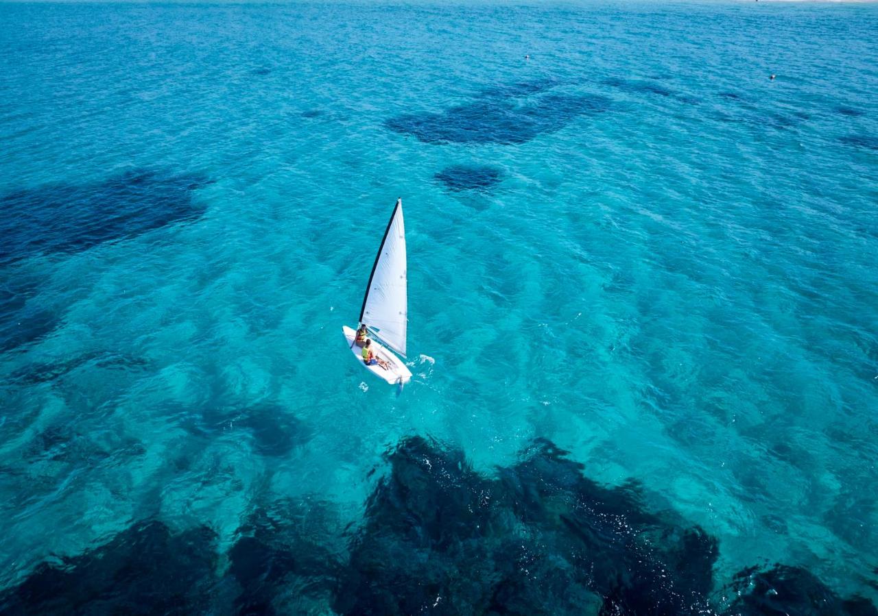 een kleine zeilboot op het blauwe water bij Calaserena Resort in Geremèas