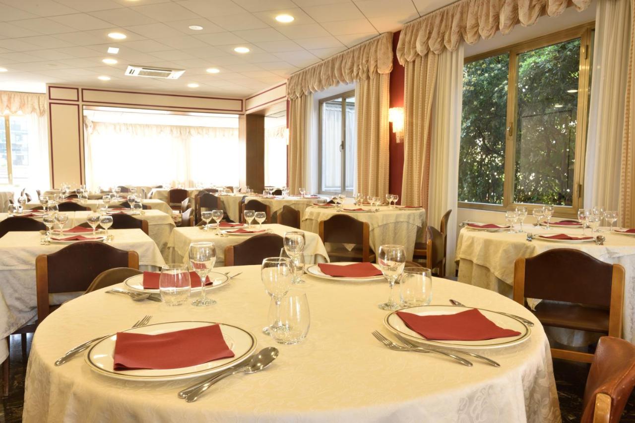 een eetkamer met tafels en stoelen met wit servies bij Hotel Bergamo Mare Mhotelsgroup in San Bartolomeo al Mare