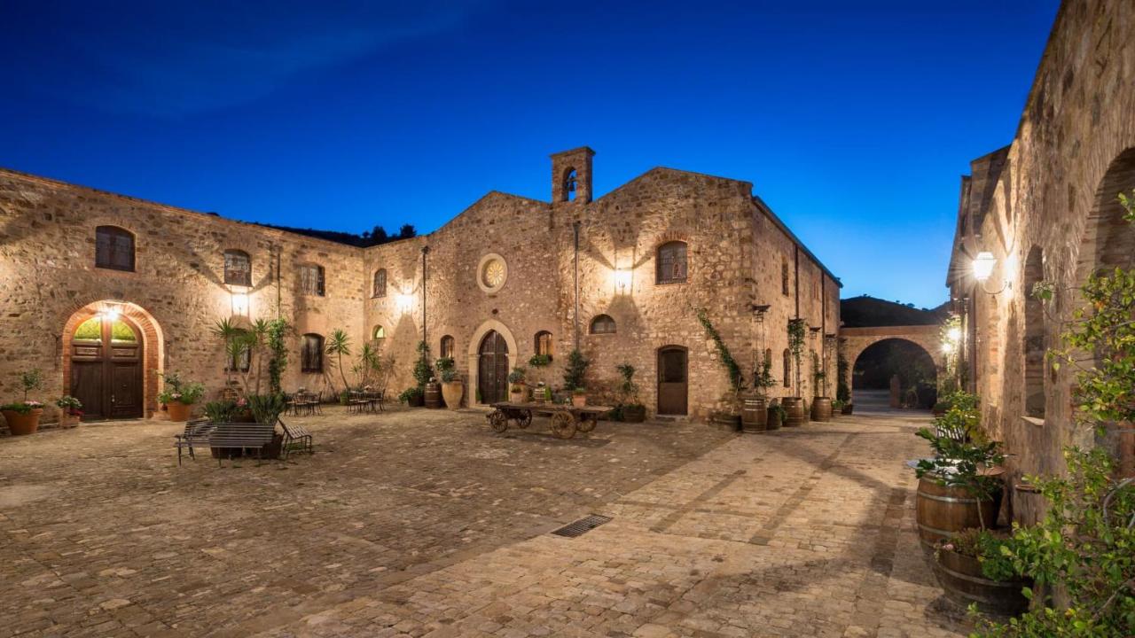 een groot stenen gebouw met een binnenplaats 's nachts bij Relais Abbazia Santa Anastasia Resort & Winery in Castelbuono