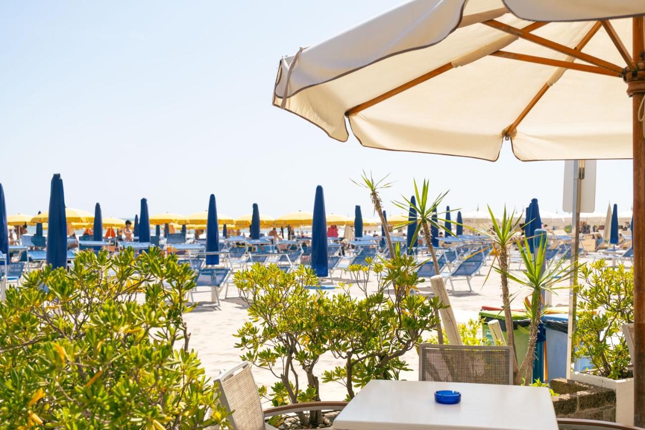 een terras met parasol, tafels en stoelen bij Hotel King - Azzurro Club in Milano Marittima