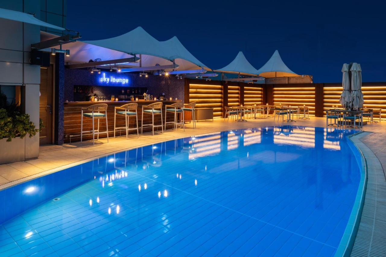 een zwembad 's nachts met een bar bij Meliá Athens in Athene
