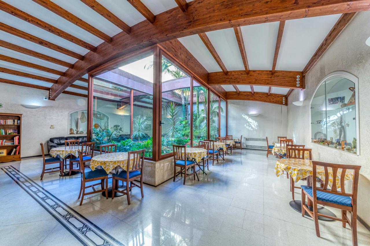 een eetkamer met tafels en stoelen en grote ramen bij Hotel Le Torri in Arborea 