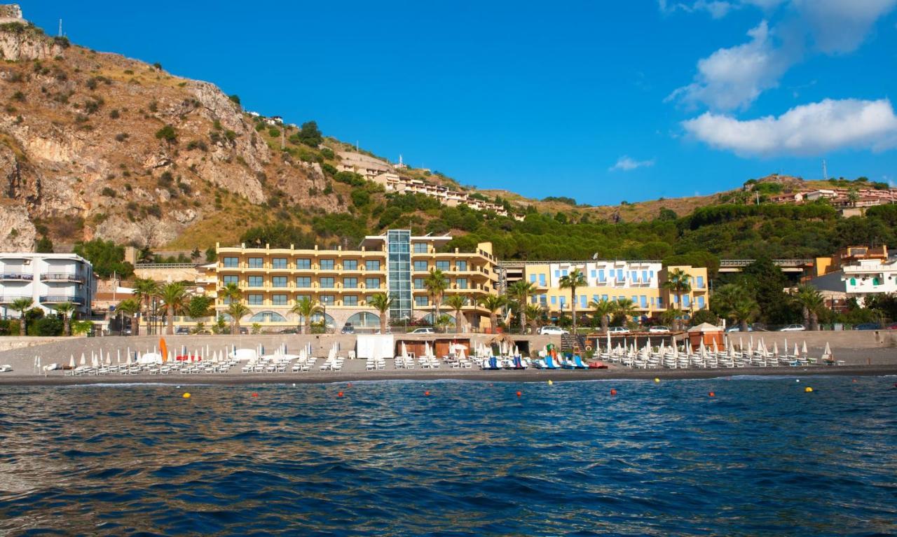 een uitzicht op een strand met stoelen en gebouwen bij Elihotel in SantʼAlessio Siculo
