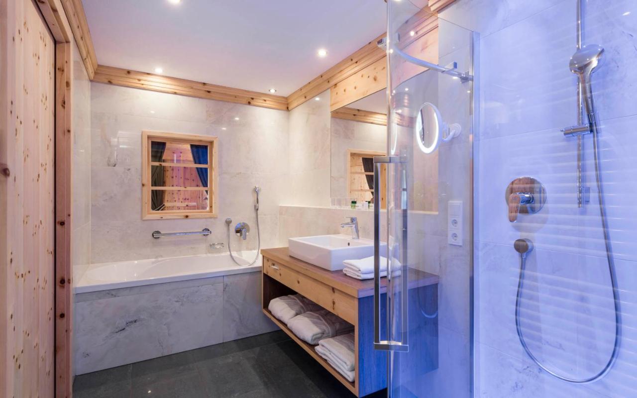 een badkamer met een douche, een wastafel en een badkuip bij Hotel Grüner Baum in Bressanone