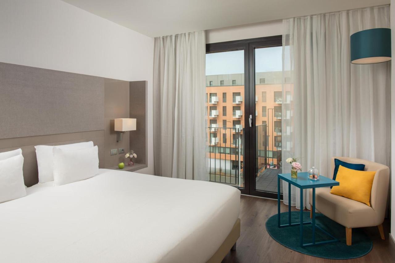 een hotelkamer met een bed, een stoel en een raam bij NH Parma in Parma