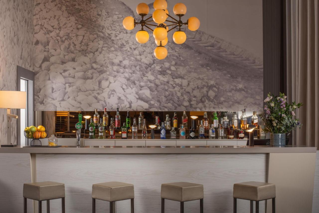 een bar met barkrukken voor een toonbank bij NH Parma in Parma