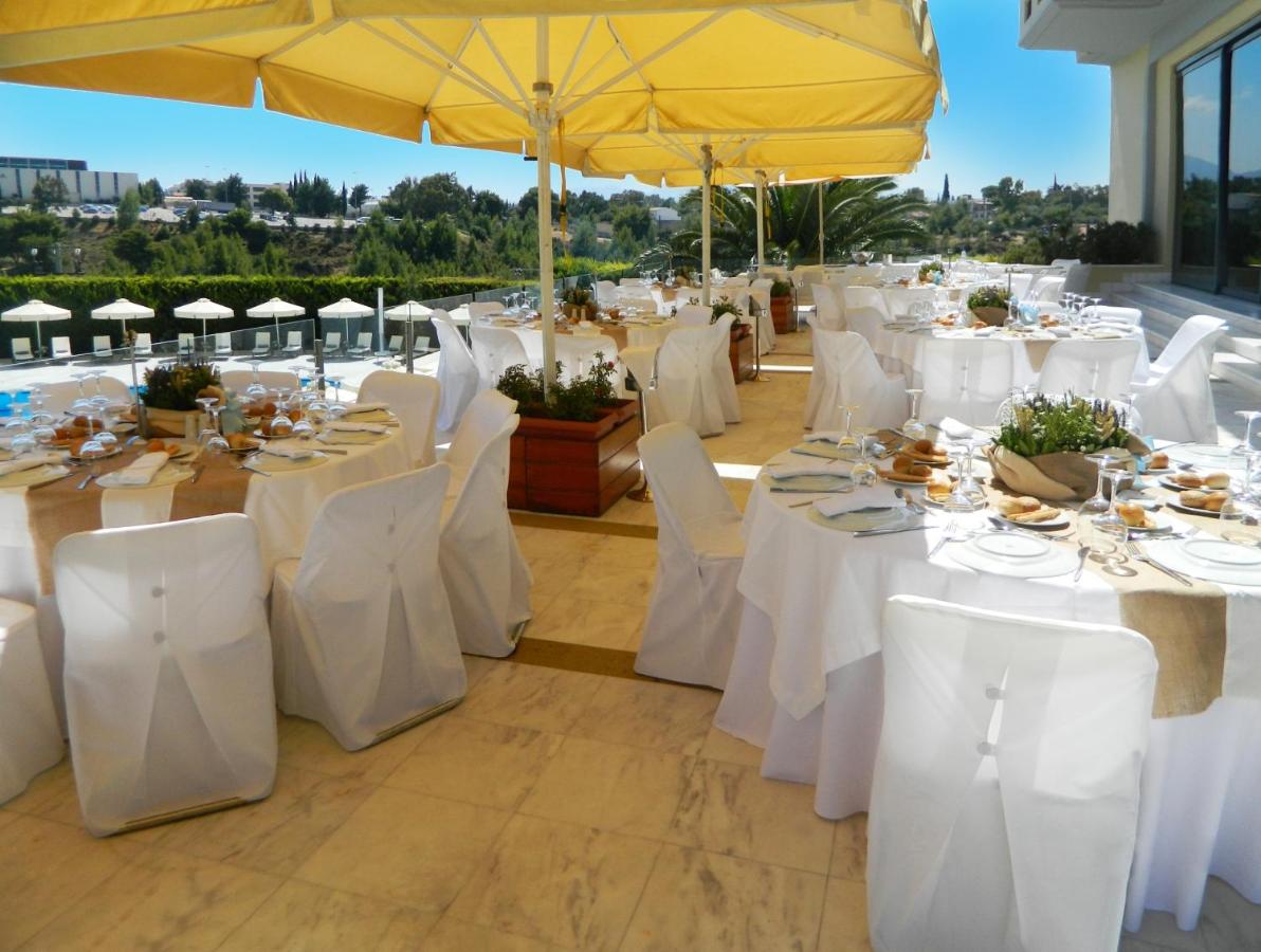 een groep tafels met witte stoelen en parasols bij Dekelia Hotel in Athene