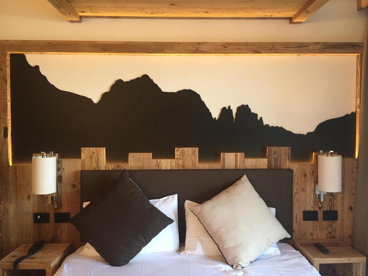 een slaapkamer met een bed waarboven een muurschildering van een berglandschap hangt bij Hotel alle Rose Family inspired