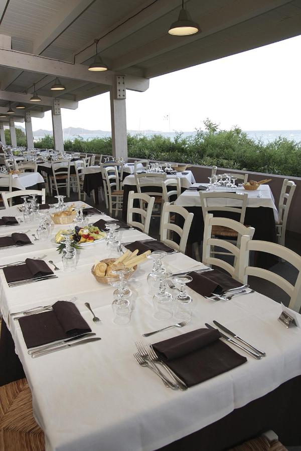 een groep tafels en stoelen met witte tafelkleden bij TH Costa Rei - Free Beach Resort in Monte Nai