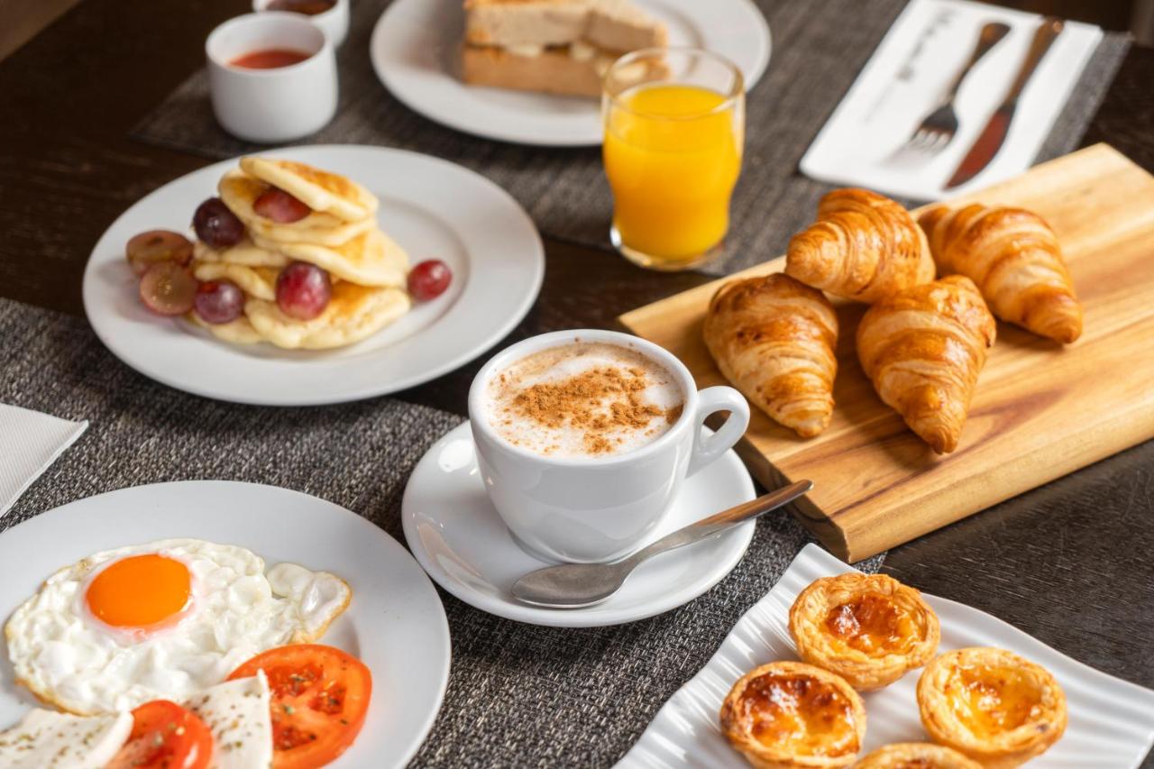 een tafel met borden vol ontbijtgerechten en een kop koffie bij HF Fénix Porto in Porto