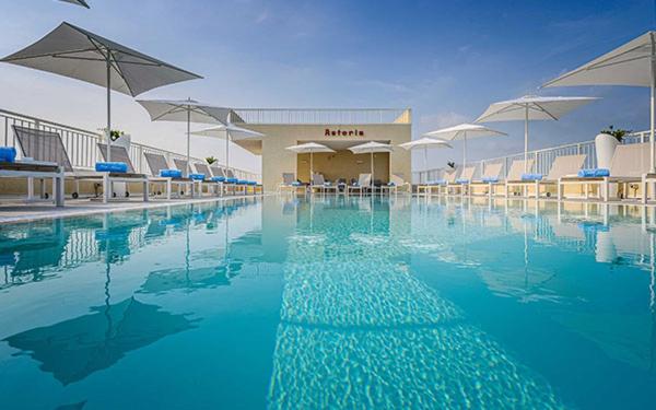 een zwembad met blauw water en parasols bij Hotel Astoria in Bibione