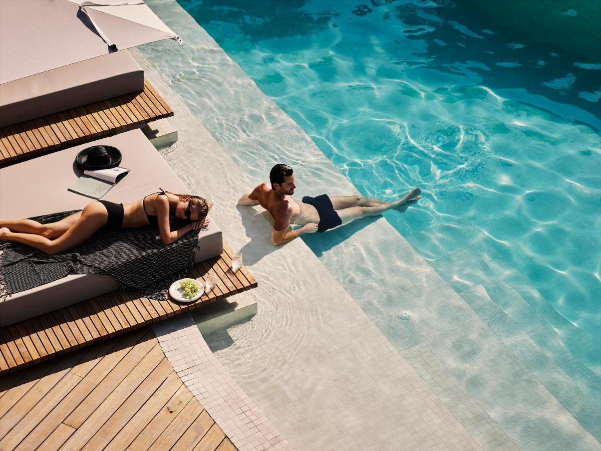 twee mensen die in een zwembad zwemmen bij San Antonio Corfu Resort (Adults Only) in Kalámi