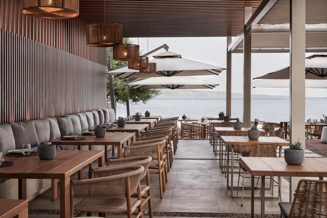 een restaurant met tafels en stoelen met de oceaan op de achtergrond bij San Antonio Corfu Resort (Adults Only) in Kalám