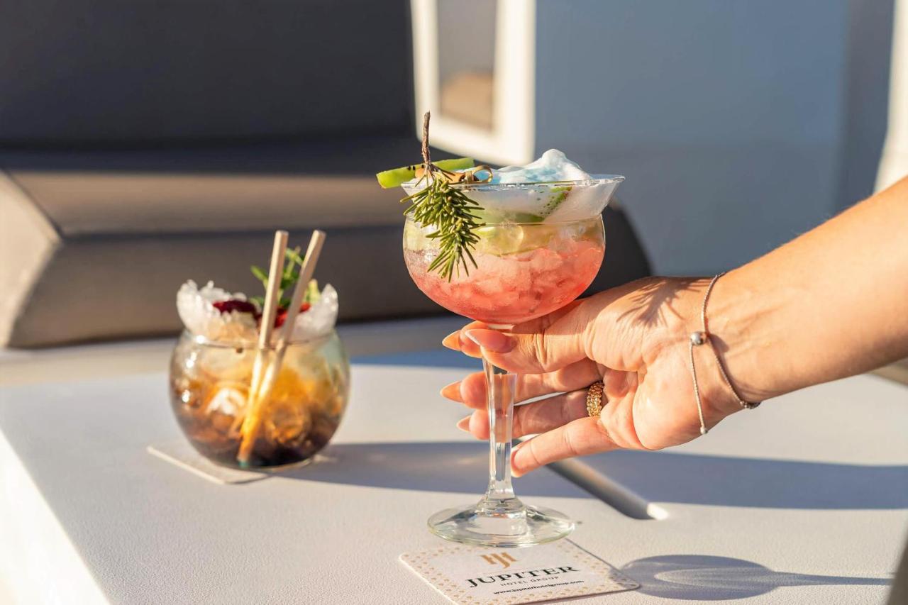 een persoon die een cocktail in een glas op een tafel houdt bij Jupiter Lisboa Hotel - Rooftop & Spa in Lissabon