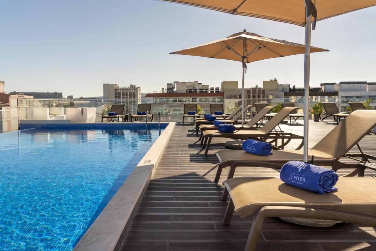 een zwembad met ligstoelen en parasols op een dak bij Jupiter Lisboa Hotel - Rooftop & Spa in Lissabon