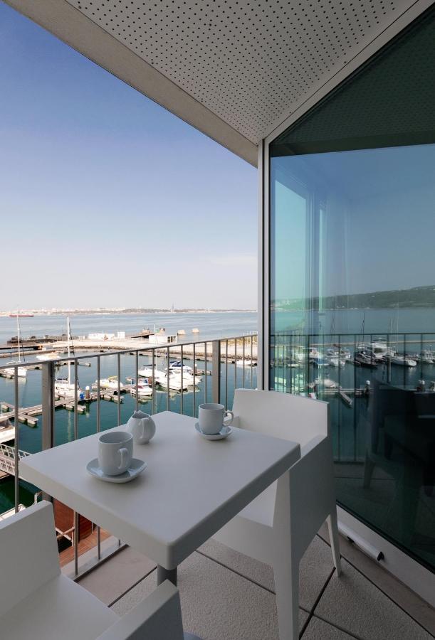 een witte tafel met stoelen en uitzicht op de oceaan bij Troia Residences - Apartamentos Marina in Troia