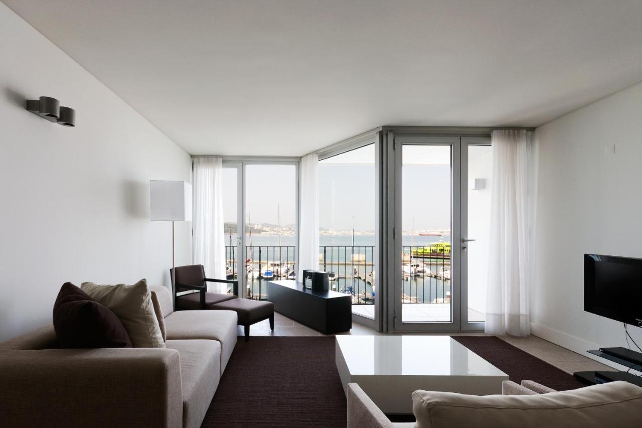 een woonkamer met een bank en een groot raam bij Troia Residences - Apartamentos Marina in Troia