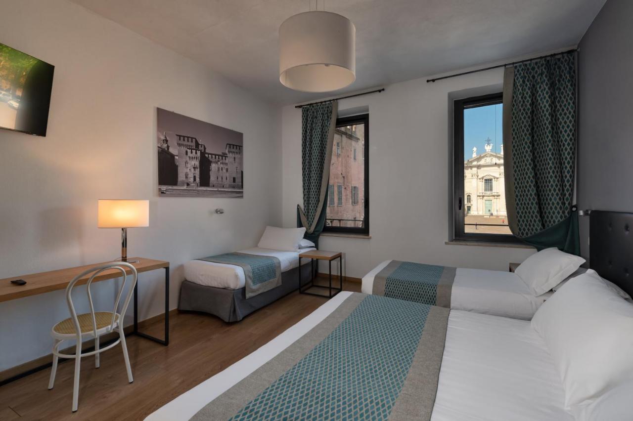 een hotelkamer met een bed en een bureau en een bed en raam bij Hotel dei Gonzaga, MantegnaHotels in Mantova