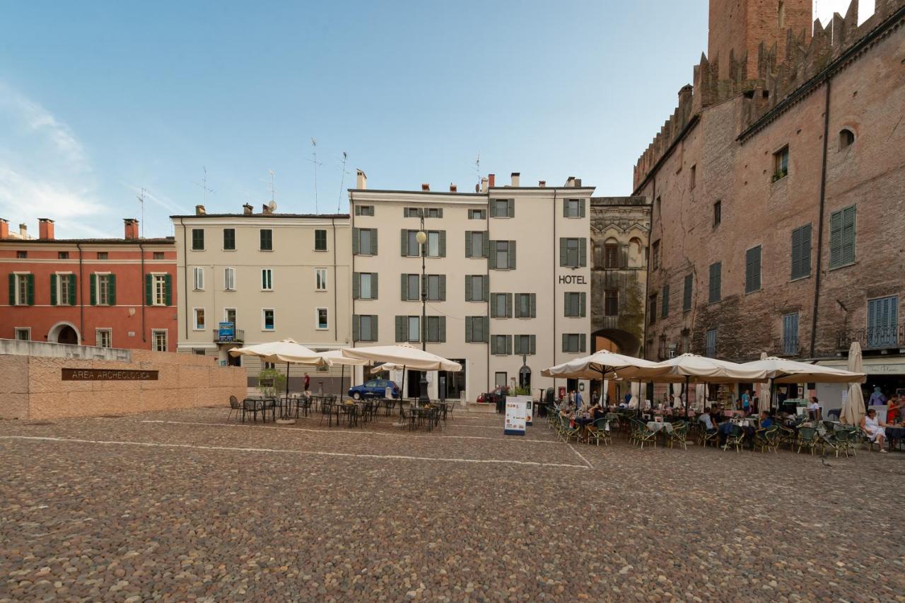 een groep tafels en parasols op een binnenplaats met gebouwen bij Hotel dei Gonzaga, MantegnaHotels in Mantova
