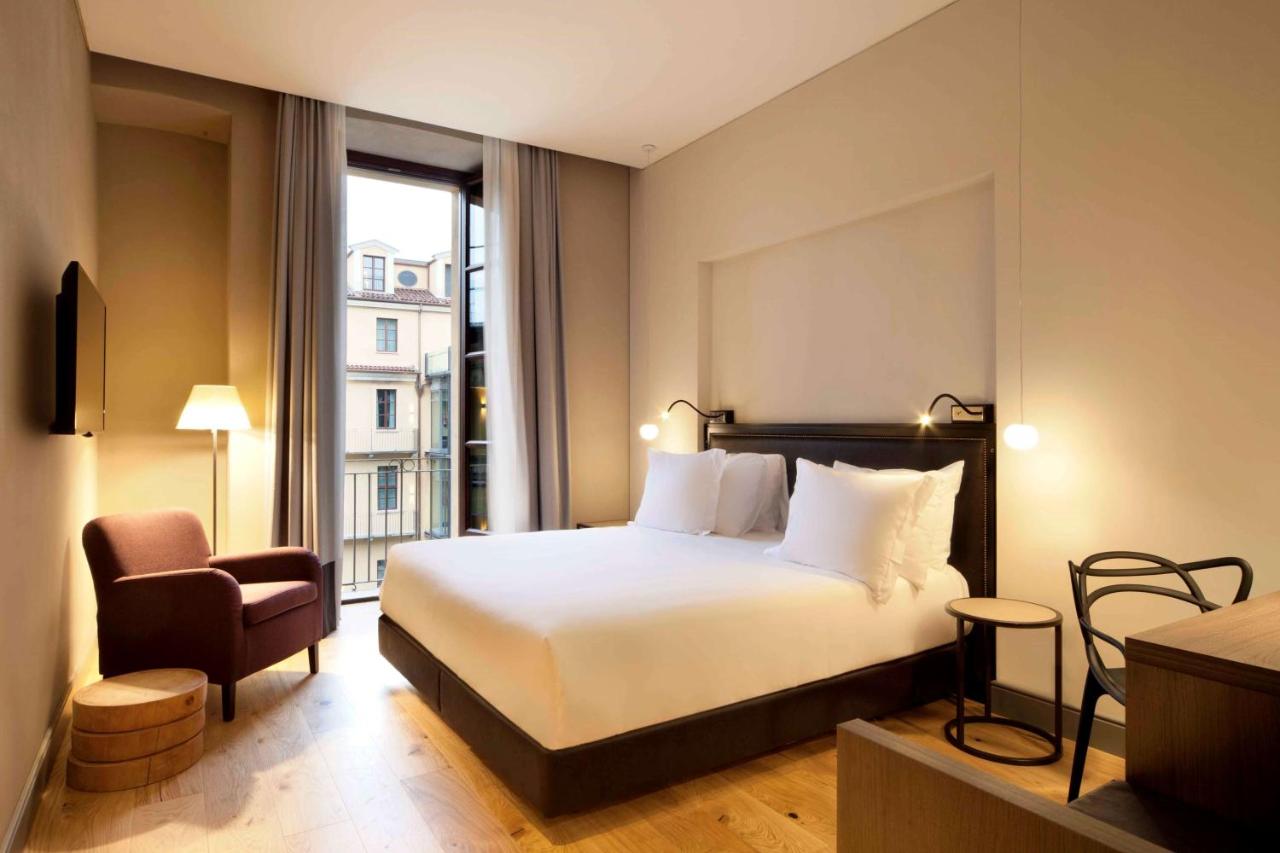 een hotelkamer met een bed en een stoel bij NH Collection Torino Piazza Carlina in Turijn