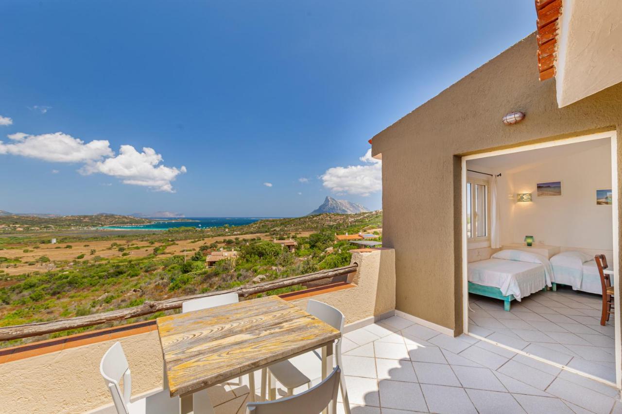 een terras met een houten tafel en stoelen op een balkon bij Residence Hotel Lu Nibareddu in San Teodoro