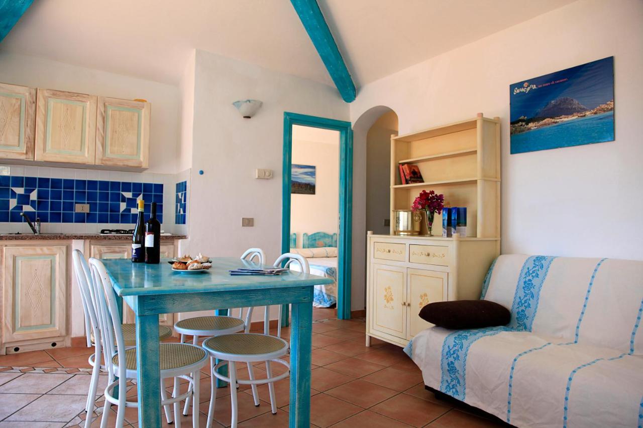 een keuken en woonkamer met een tafel en een bank bij Residence Hotel Lu Nibareddu in San Teodoro