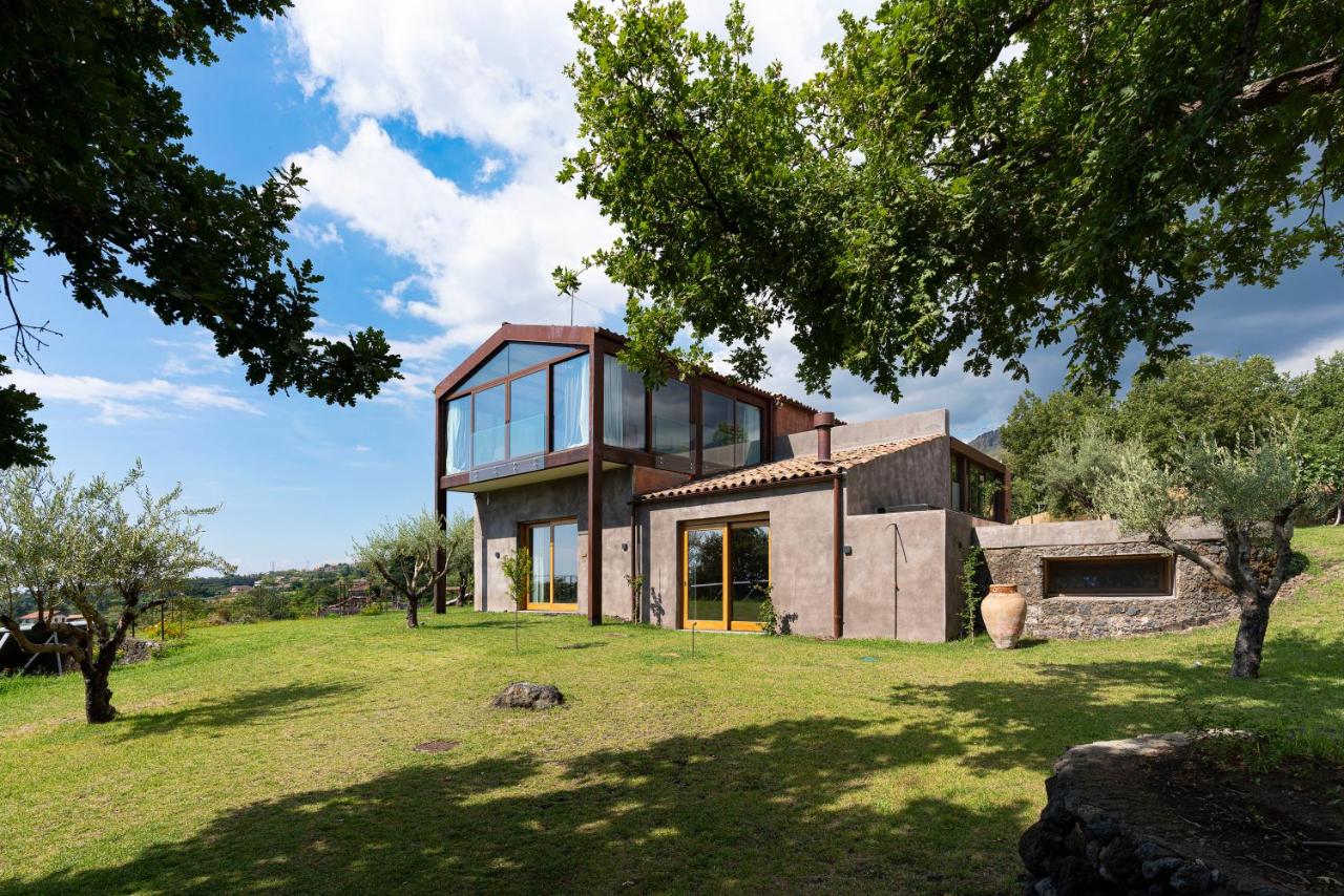 een huis met glazen ramen op een groen veld bij Monaci delle Terre Nere in Zafferana Etnea