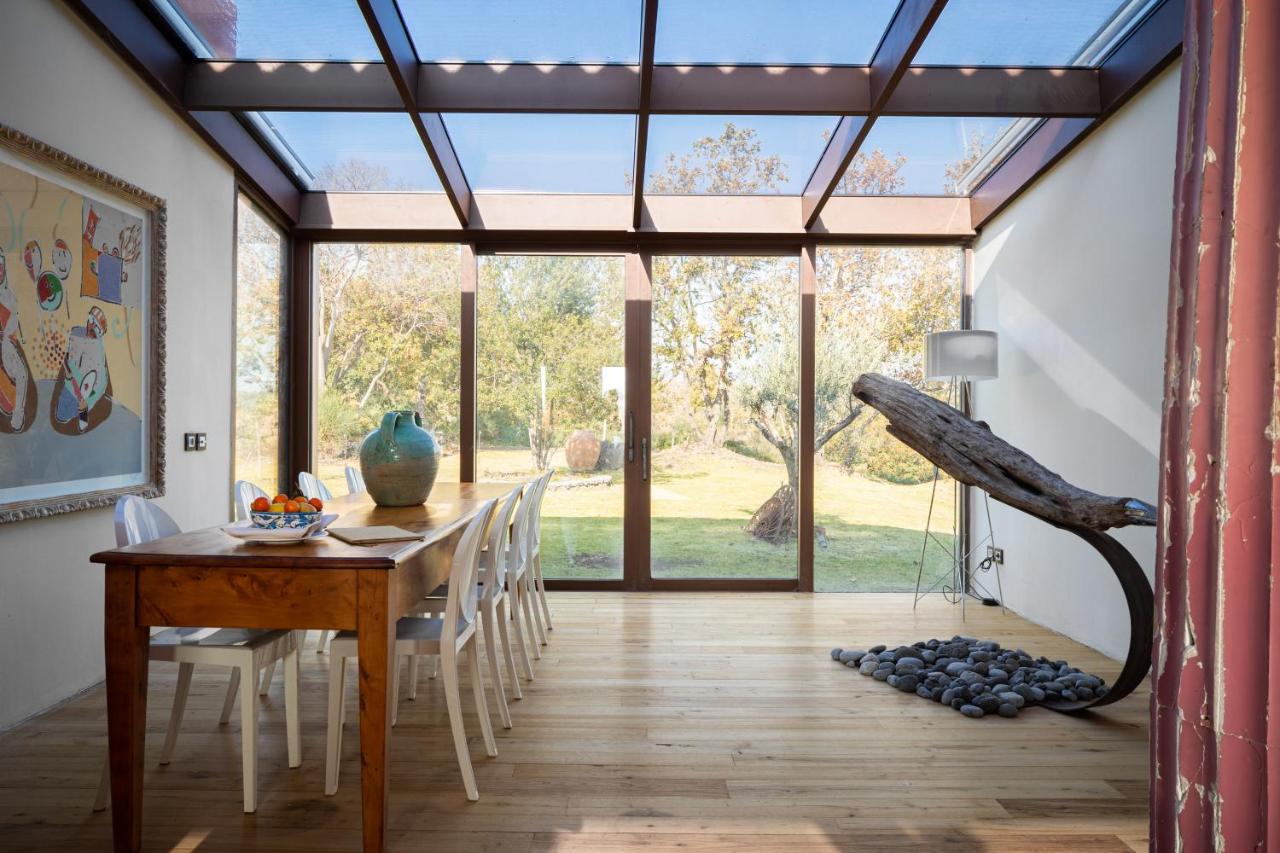 een eetkamer met een houten tafel en glazen ramen bij Monaci delle Terre Nere in Zafferana Etnea