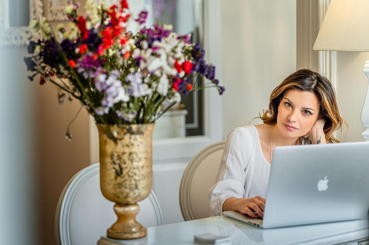 een vrouw zit aan een tafel en gebruikt een laptop. bij B&B Palazzo Cerami in Catania