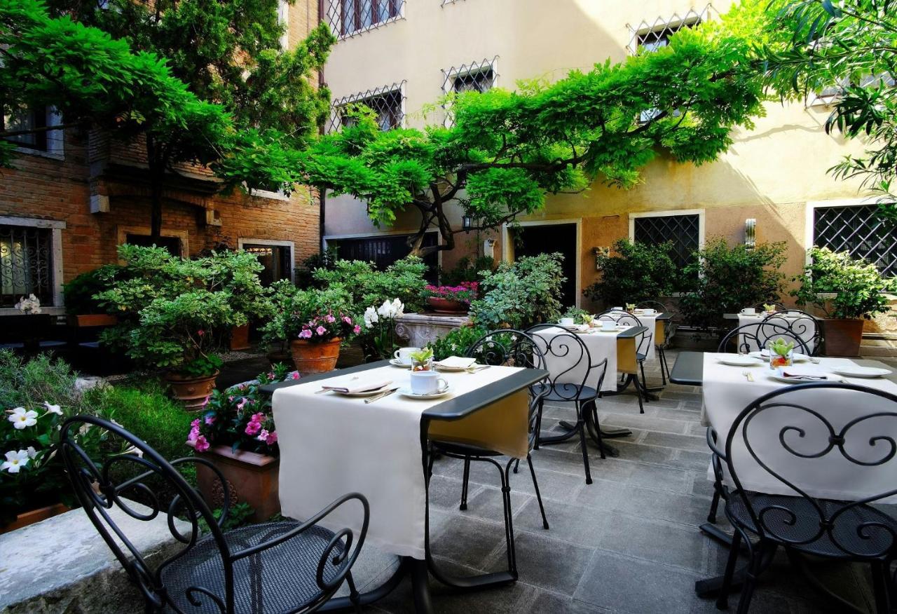 een restaurant met witte tafels en stoelen en bomen bij Sina Palazzo Sant'Angelo in Venetië