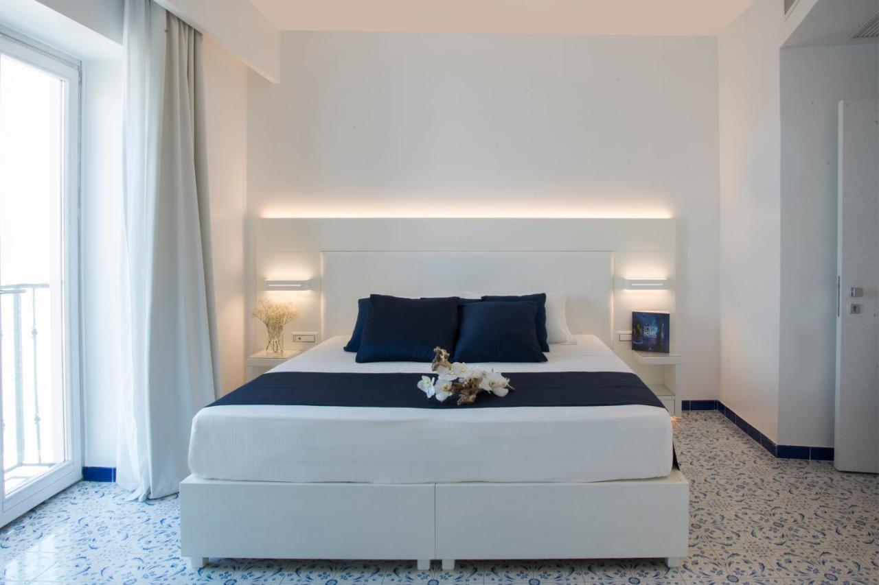 een slaapkamer met een groot wit bed met blauwe kussens bij Lloyd's Baia Hotel in Vietri