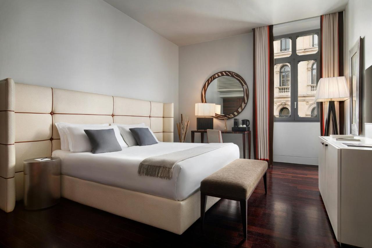 een slaapkamer met een groot wit bed en een spiegel bij Sina The Gray in Milaan