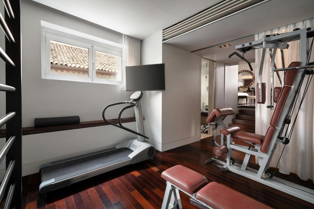 een fitnessruimte met een loopband en een spiegel bij Sina The Gray in Milaan +18 foto's