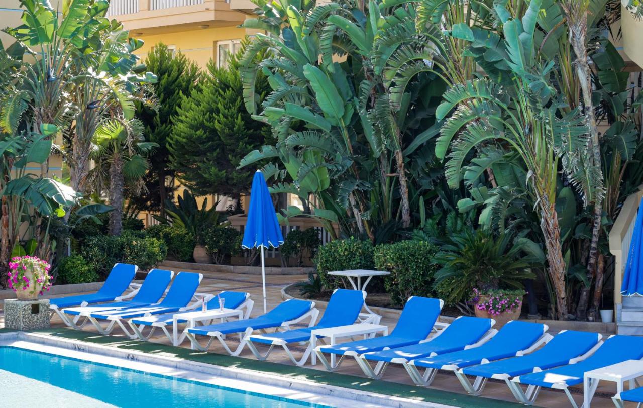 een rij stoelen en parasols naast een zwembad bij Futura Hotel in Maleme