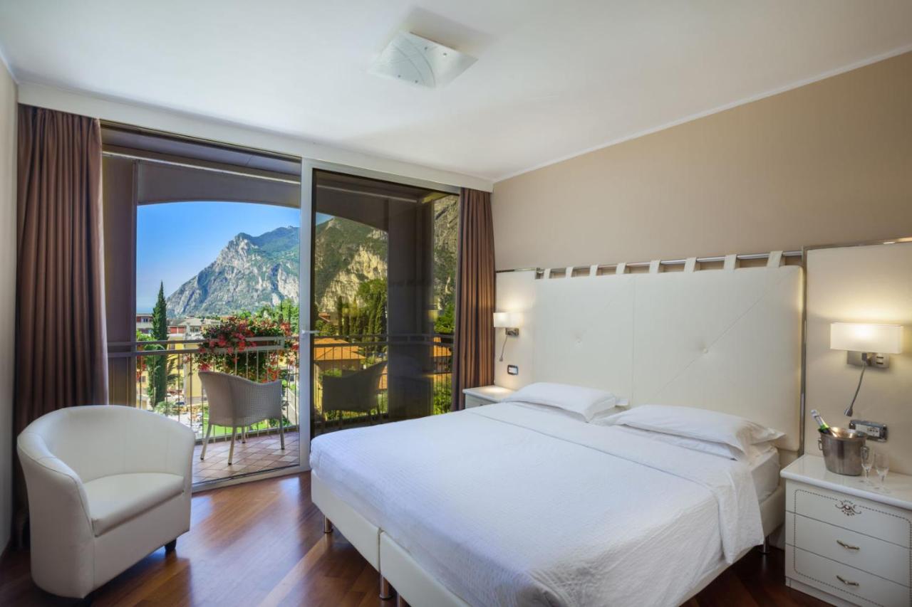 een slaapkamer met een groot wit bed en een balkon bij Hotel Savoy Palace - Tonelli Hotels in Riva del Garda