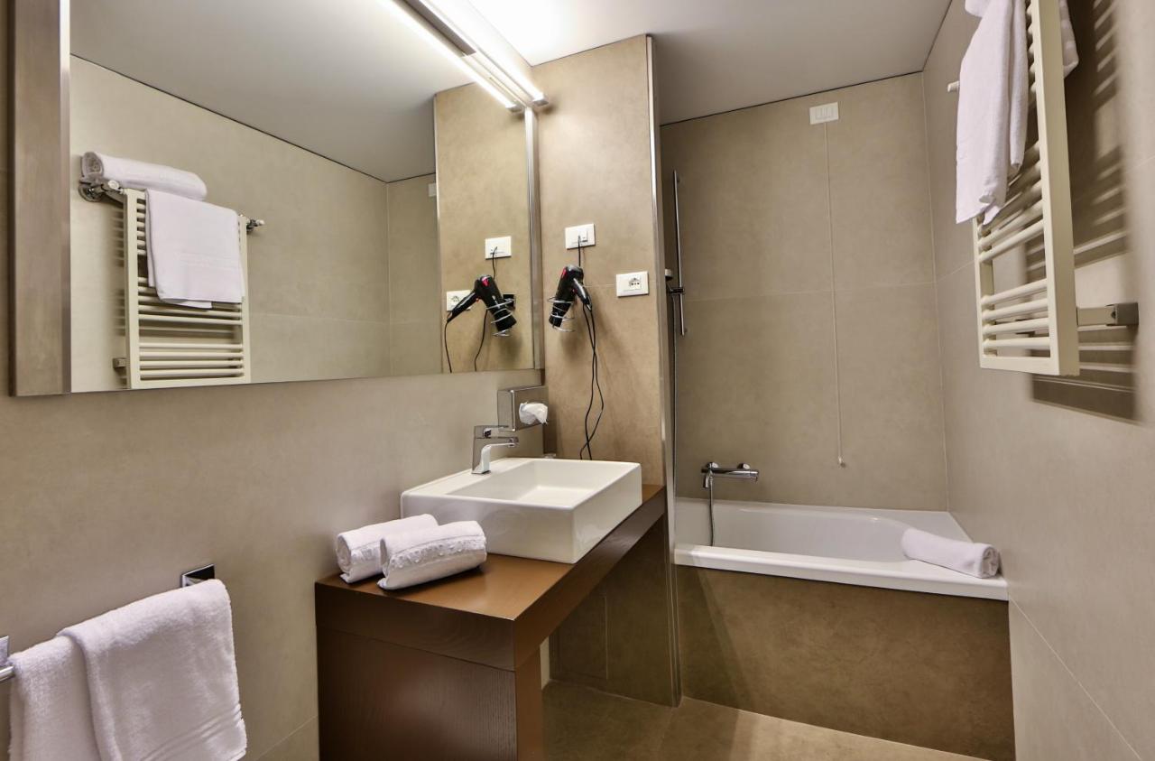 een badkamer met een wastafel, een badkuip en een spiegel bij Bonotto Hotel Belvedere in Bassano del Grappa